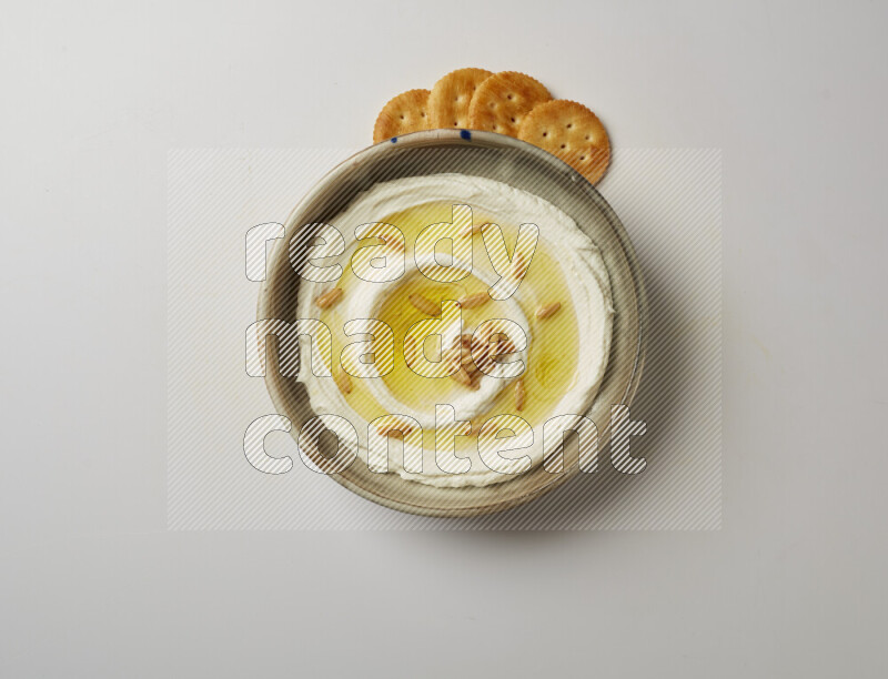 Lebnah garnished with pine nuts in a grey pottery plate on a white background