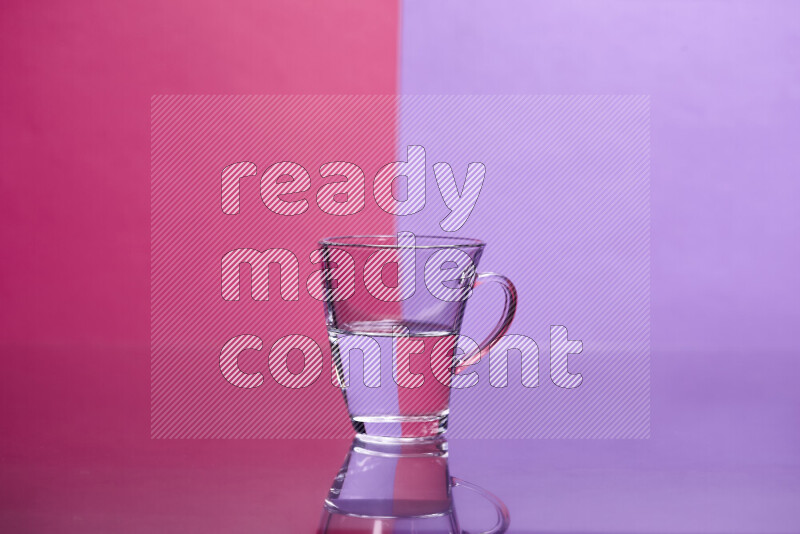 The image features a clear glassware filled with water, set against pink and light purple background