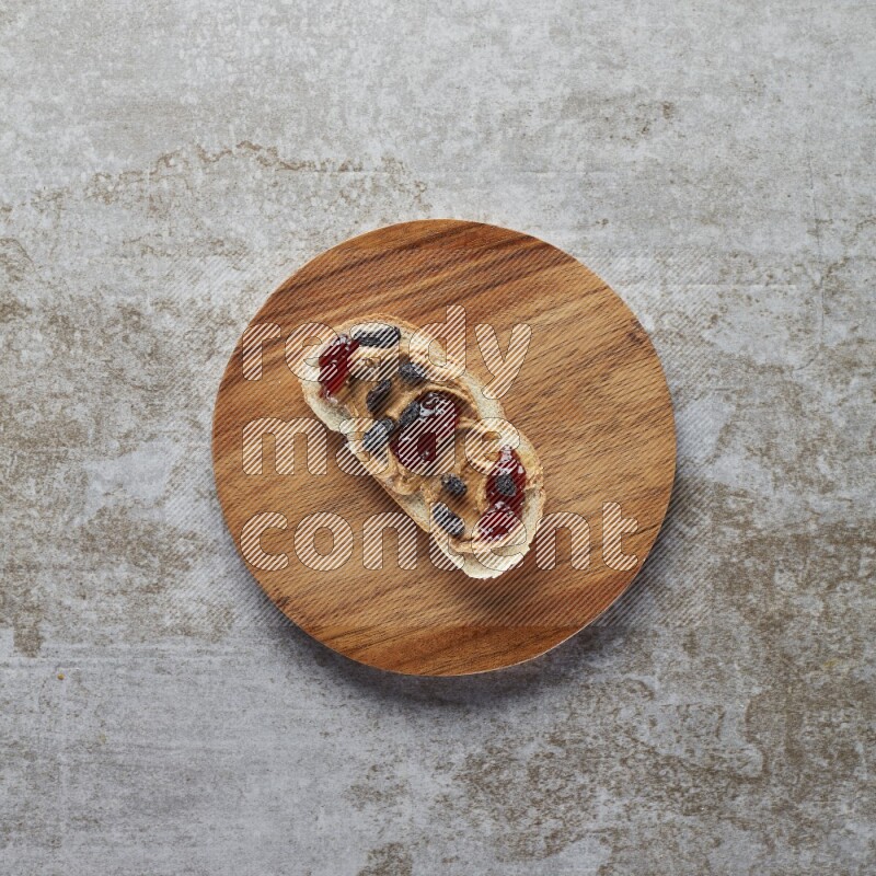 open faced peanut butter sandwich with jam and dried cranberries on a grey textured background