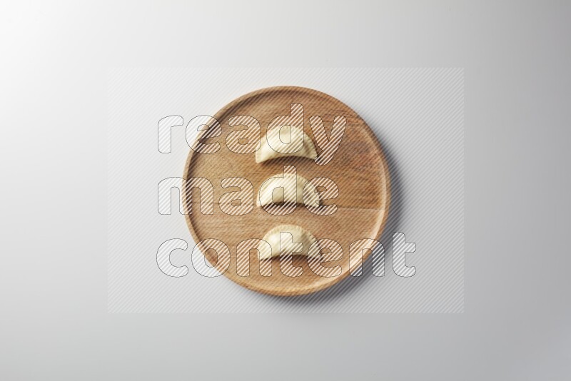 Three Sambosas on a wooden round plate on a white background