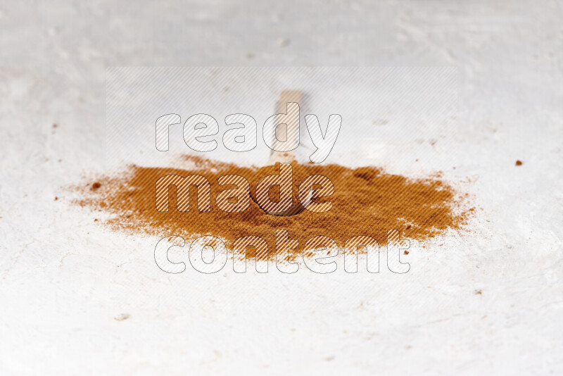 A wooden spoon full of ground paprika powder and surrounded with the powder on white background