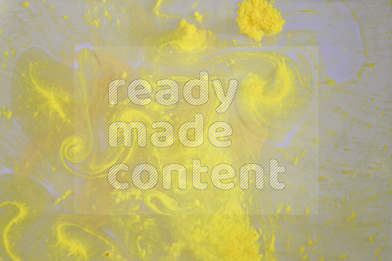 The image captures a dramatic splatter of yellow paint over a white backdrop