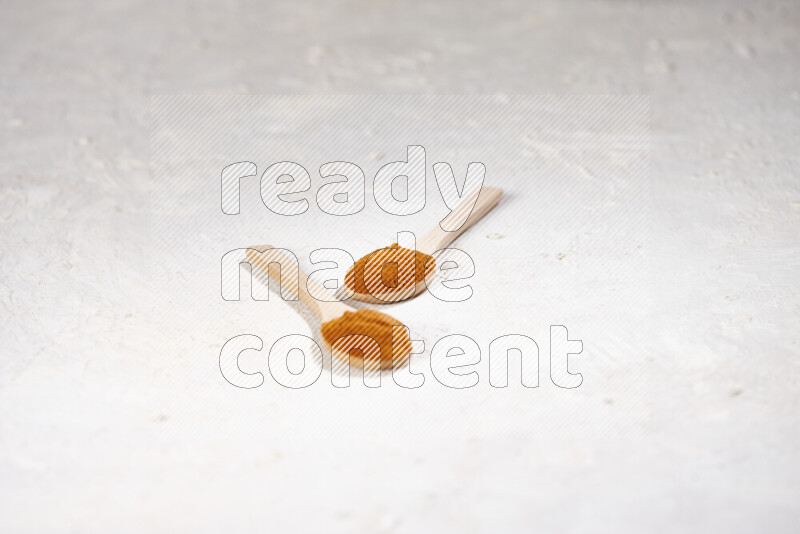 Two wooden spoons full of ground paprika powder on white background