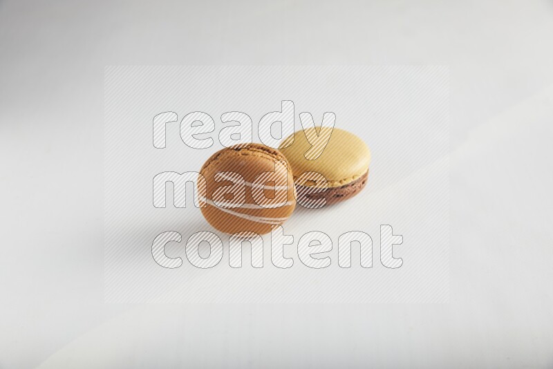 45º Shot of of two assorted Brown Irish Cream, and Yellow, and Brown Chai Latte macarons on white background