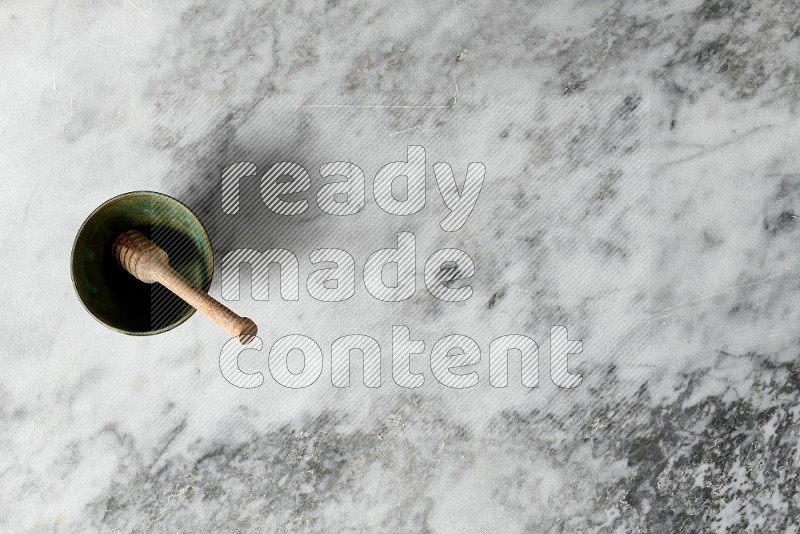 Multicolored Pottery Bowl with wooden honey handle in it, on grey marble flooring, Top View