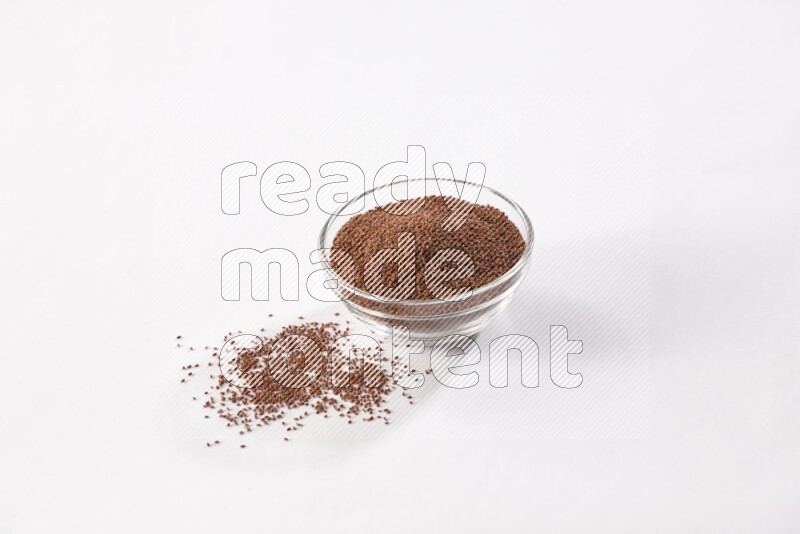 وعاء زجاجي ممتلئ ببذور حب الرشاد مع بعض البذور متناثرة على خلفية بيضاء