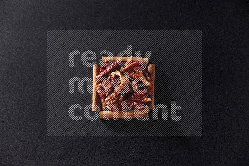 A single square of cinnamon sticks full of chilis on black flooring