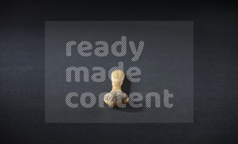 A wooden spoon full of cardamom powder on black flooring