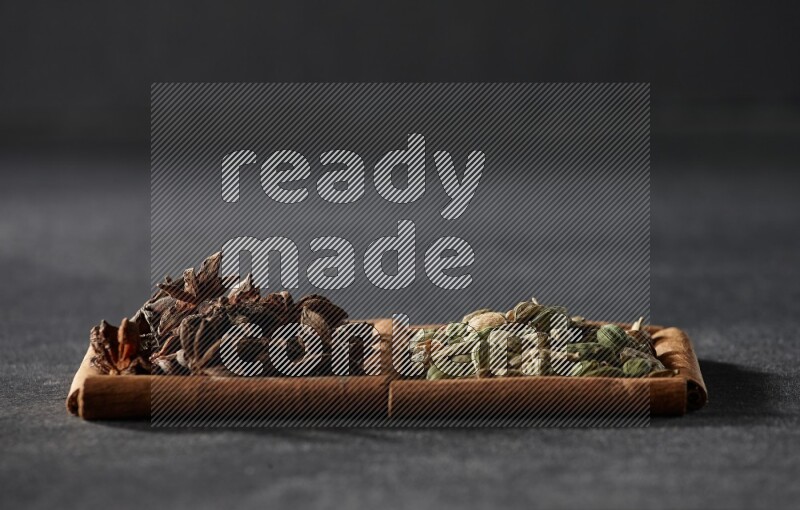 2 squares of cinnamon sticks full of cardamom and star anise on black flooring