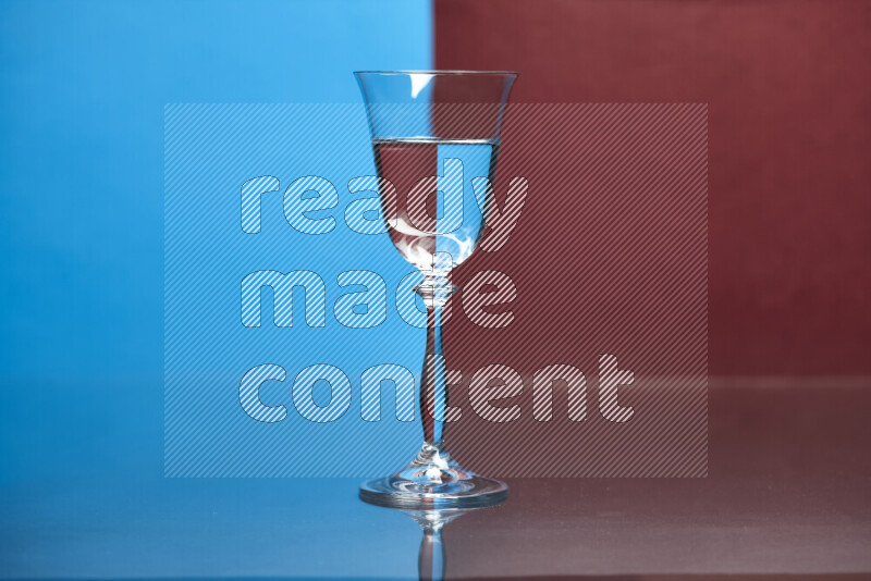 The image features a clear glassware filled with water, set against blue and dark red background