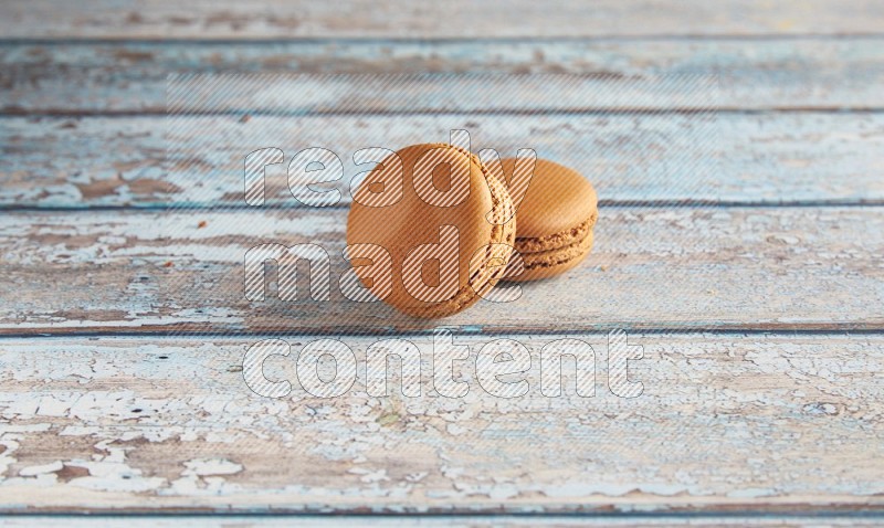 45º Shot of two Brown Maple Taffy macarons on light blue wooden background