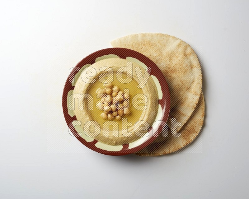 Hummus in a traditional plate garnished with roasted chickpeas  on a white background