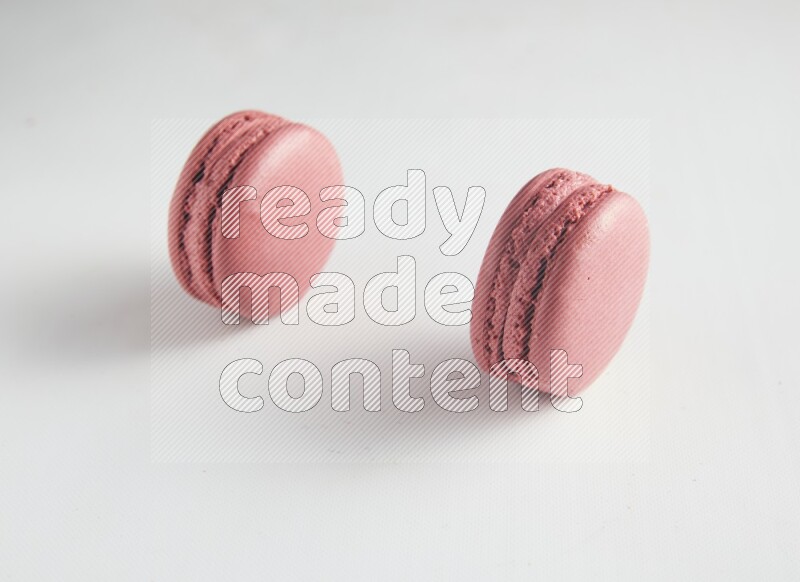 45º Shot of two Pink Raspberry macarons on white background