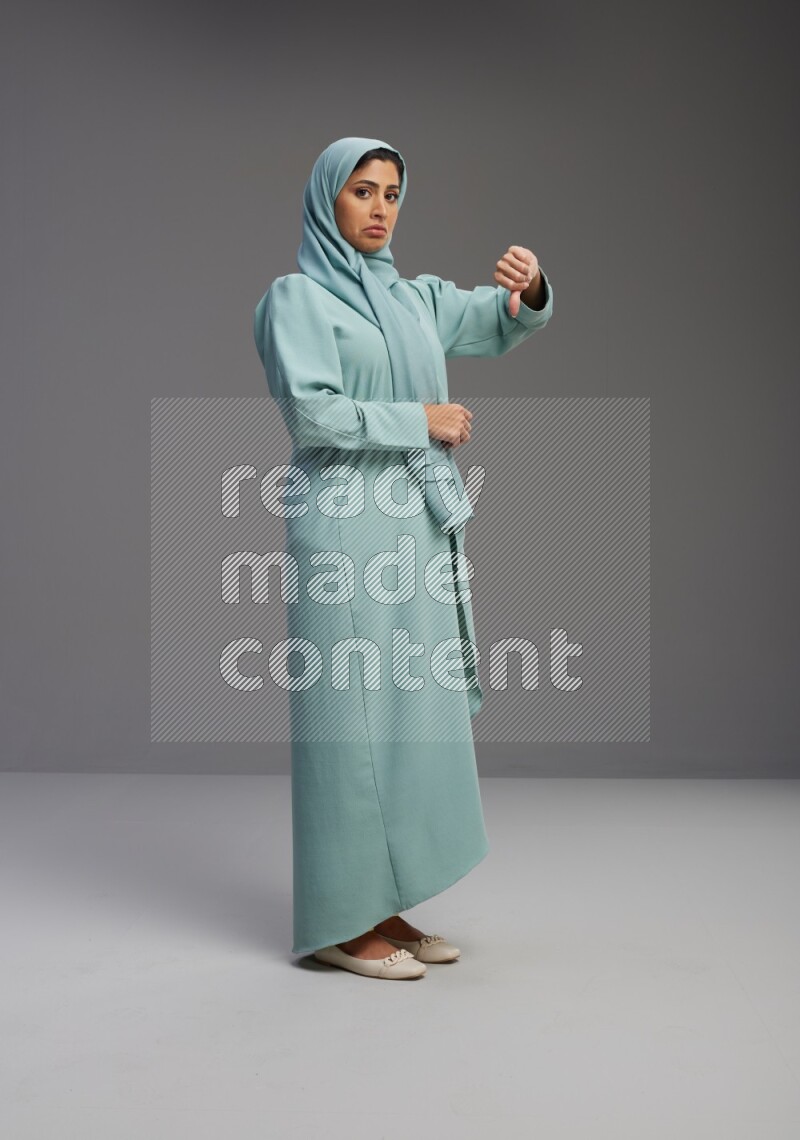 Saudi Woman wearing Abaya standing interacting with the camera on Gray background