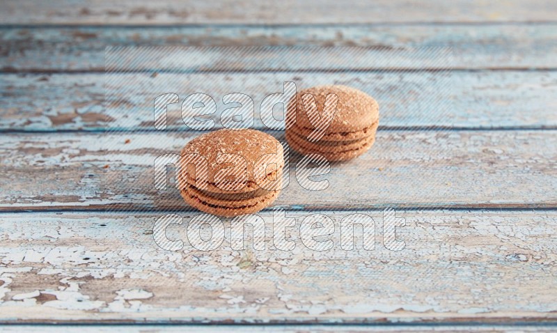 45º Shot of two Brown Hazelnuts macarons on light blue wooden background