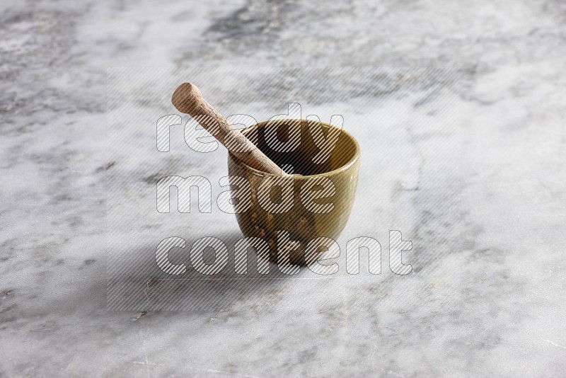 Multicolored Pottery Cup with wooden honey handle in it, on grey marble flooring, 45 degree angle