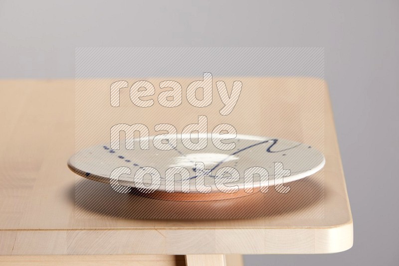 multi-colored pottery Plate on a wooden table edge