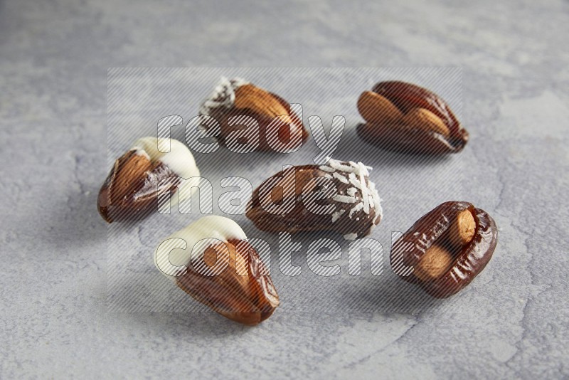 Group of Almonds stuffed dates plain and covered with chocolate on a light grey background