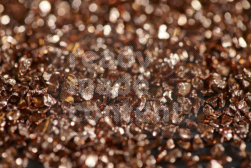 Bronze shimmering fragments of glass scattered on a black background