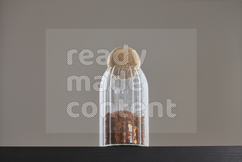 Sequins in a glass jar on black background