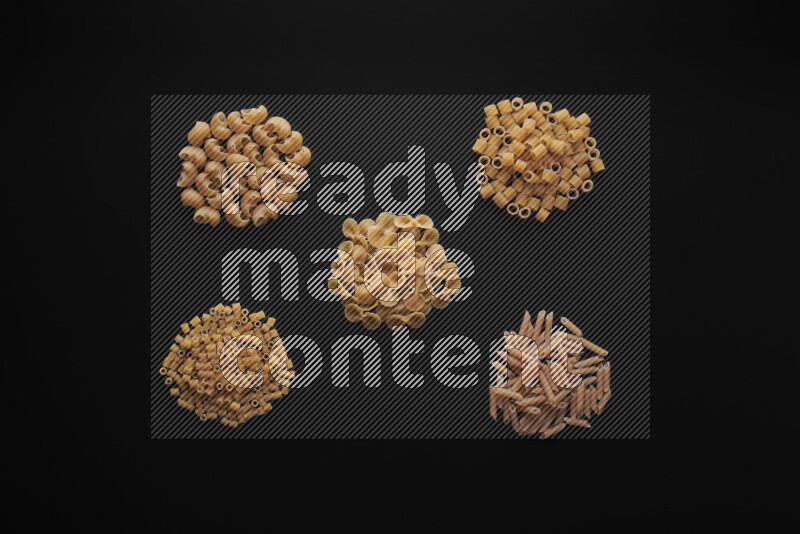 Different pasta types in bunches on black background
