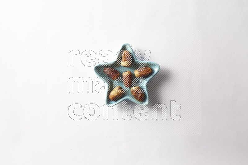 Dates in a star shaped pottery plate on white background