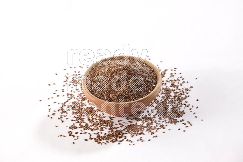 A wooden bowl full of flax surrounded by flax seeds on a white flooring in different angles