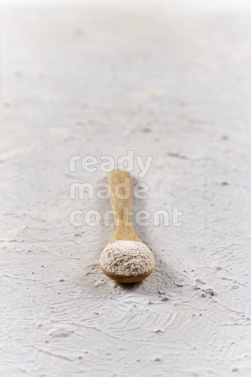 A wooden spoon full of onion powder on white background