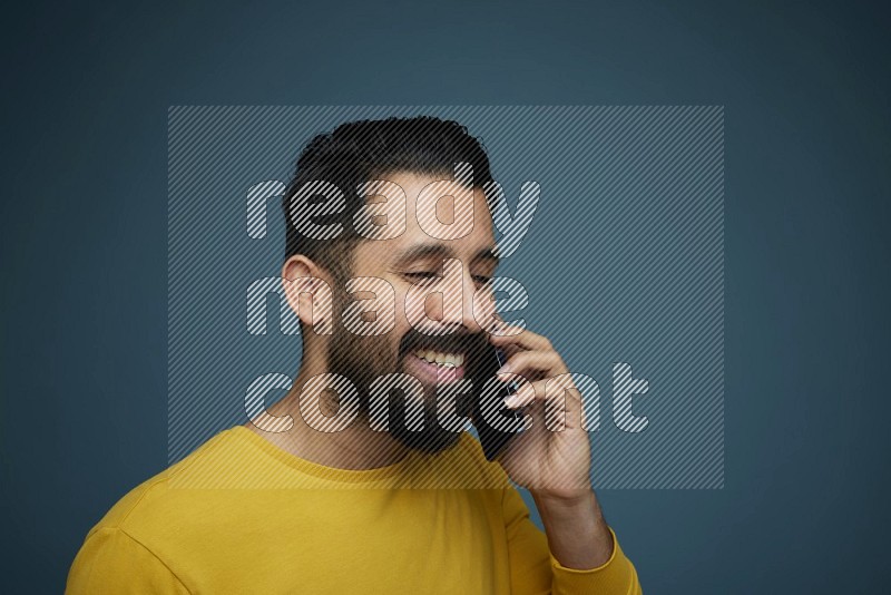 A man having a calling in a blue background wearing a yellow shirt