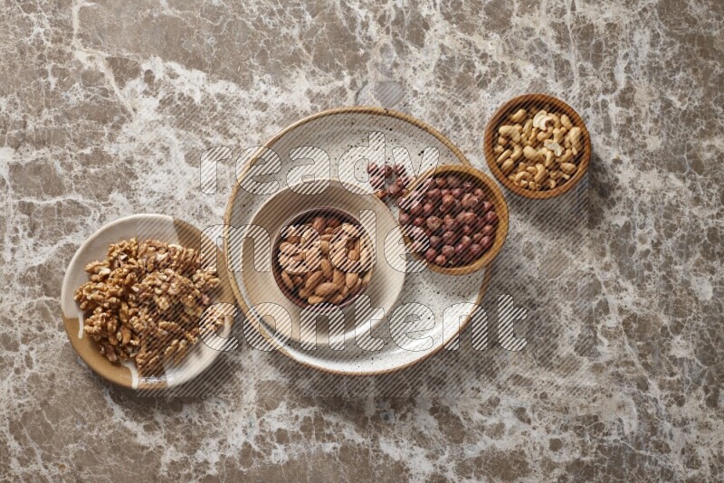 Nuts in pottery plates and wooden bowls in a light setup