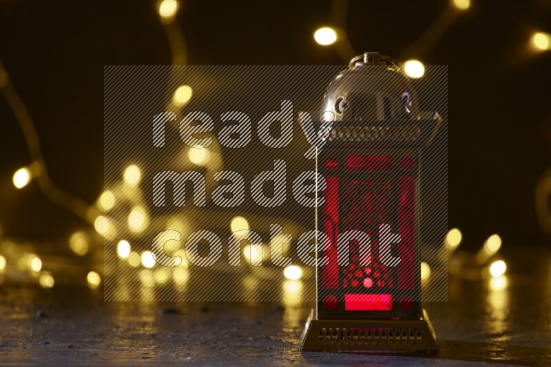 A traditional ramadan lantern surrounded by glowing fairy lights in a dark setup