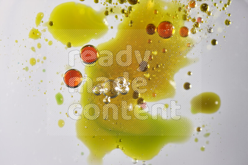 Close-ups of abstract red, green and yellow watercolor drops on oil Surface on white background