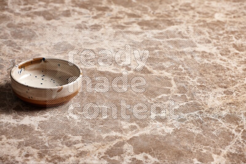 A multicolored pottery plate on beige marble background