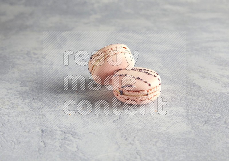 45º Shot of two pink orange blossom macarons  on white  marble background