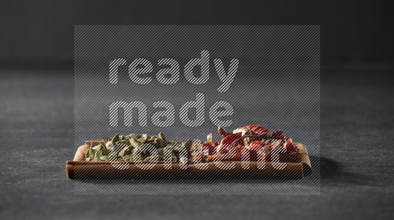 2 squares of cinnamon sticks full of chilis and cardamom on black flooring