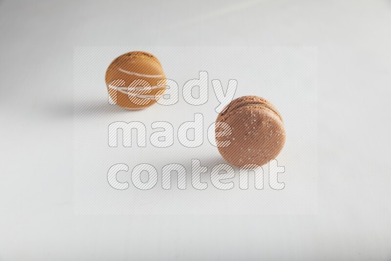 45º Shot of of two assorted Brown Irish Cream, and Brown Hazelnuts macarons on white background