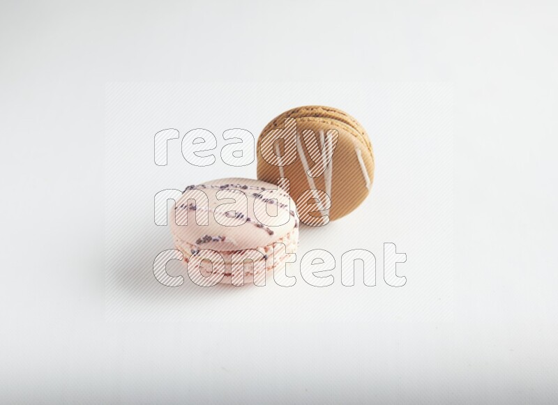 45º Shot of of two assorted Brown Irish Cream, and pink orange blossom macarons on white background