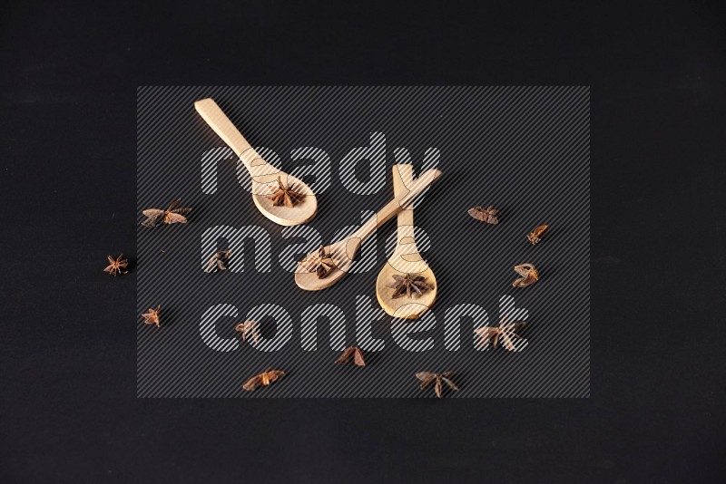 Star Anise in wooden spoons on black flooring