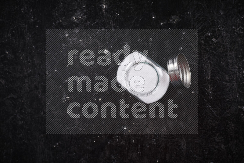 وعاء زجاجي ممتلئ بالملح الأبيض الناعم على خلفية سوداء