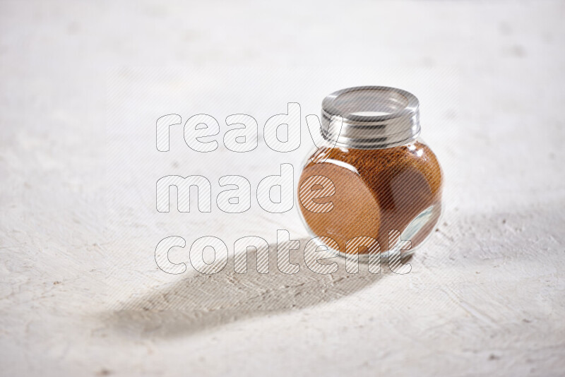 A glass jar full of ground paprika powder on white background