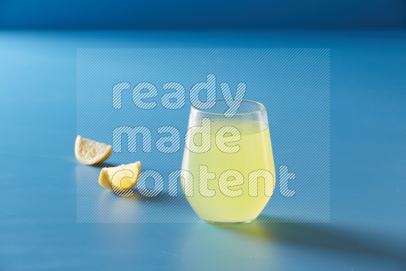 glass of lemon juice on blue background