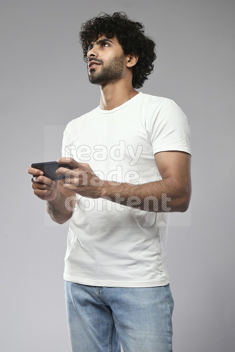 A man wearing casual standing and gaming on the phone on white background