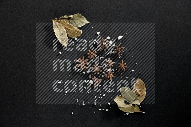 Salt, star anise and bay laurel on black flooring