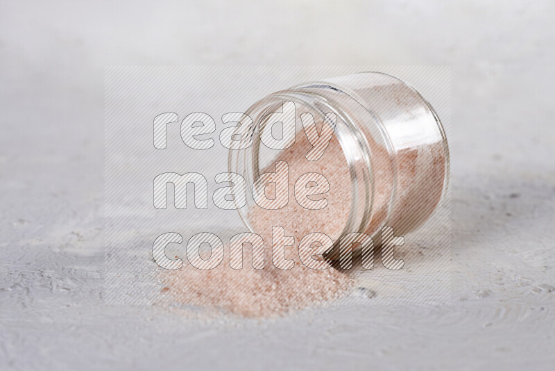 A glass jar full of fine himalayan salt on white background