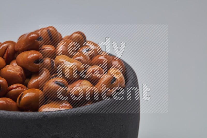 Close up shot of cooked fava beans (foul) in a container on white background