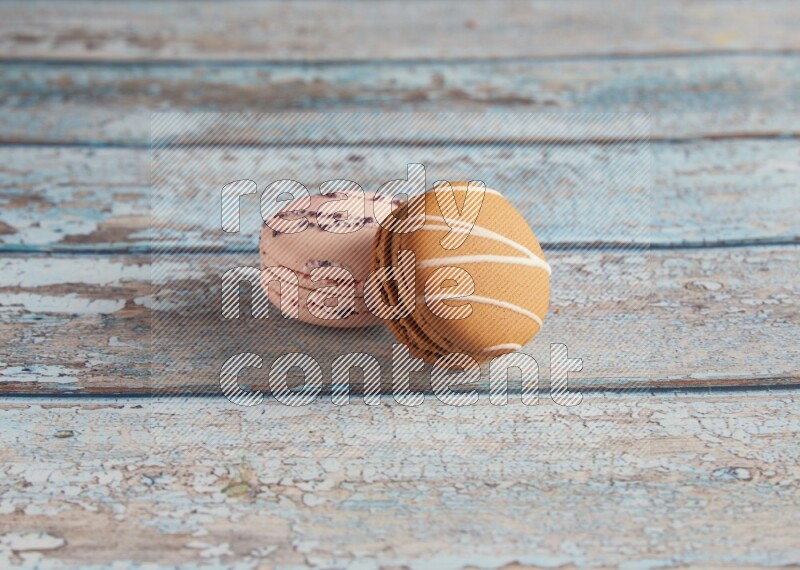 45º Shot of of two assorted Brown Irish Cream, and pink orange blossom  macarons on light blue background