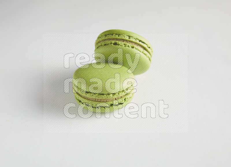 45º Shot of two Green Pistachio macarons on white background