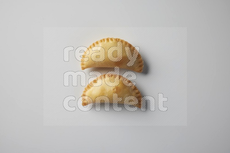 Two fried sambosa from a top angle on a white background