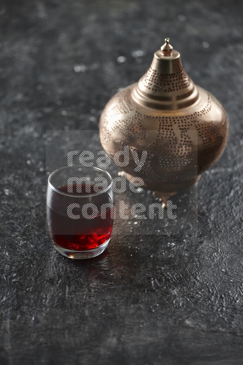 A golden lantern with different drinks, dates, nuts, prayer beads and quran on textured black background