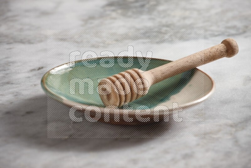 Multicolored pottery plate with wooden honey dipper in it on grey marble background